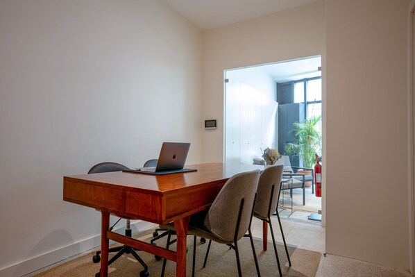 A conference room with a wooden table, two chairs, a laptop, and a small plant.