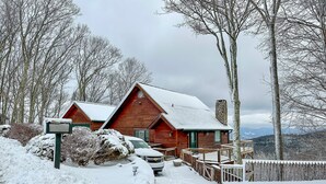 A wooden cabin with a stone foundation, surrounded by snow-covered trees and a wooden fence. - Amazing Views*HotTub*Sauna*GameRooms Dog-friendly! (Beech Mountain)