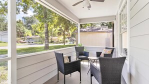 A covered porch with wicker furniture and a ceiling fan.