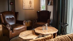 Una sala de estar acogedora con dos sillones de cuero, una mesa de centro de madera y un cuadro en la pared.