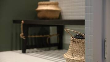 A bathroom with a woven basket on the floor, a small woven stool, and a woven basket on a shelf.