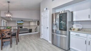 Una cucina moderna con elettrodomestici in acciaio inossidabile, mobili bianchi e un'area pranzo con sedie in legno.