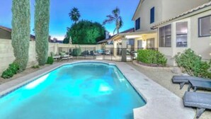 Una piscina con lettini, una terrazza e un edificio con tetto in tegole.