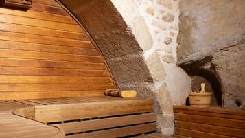 Una sauna de paredes de piedra con bancos de madera y un banco de madera con un perchero para toallas.