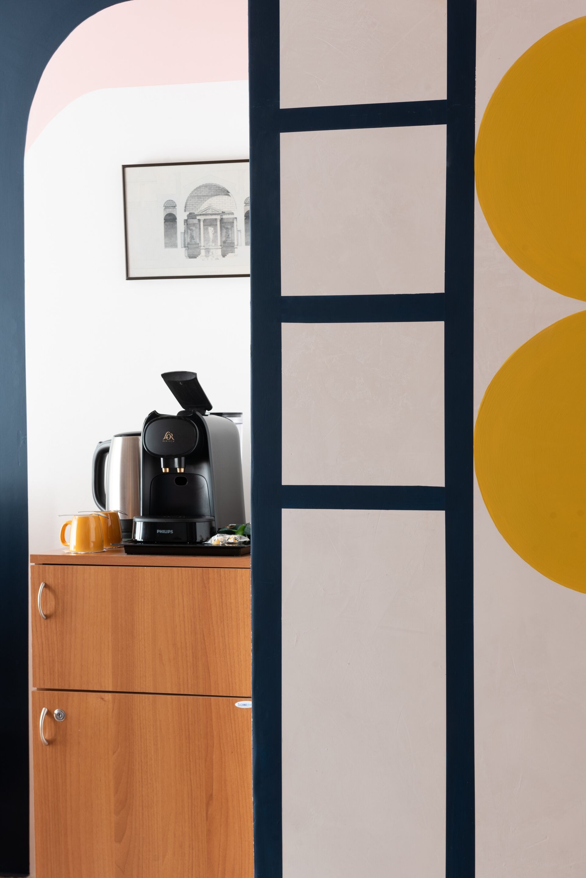 A coffee machine on a wooden cabinet with a framed picture above it.