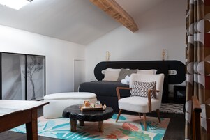 Un dormitorio moderno con una cama grande, una mesita de noche, una silla y una pequeña mesa con una bandeja.