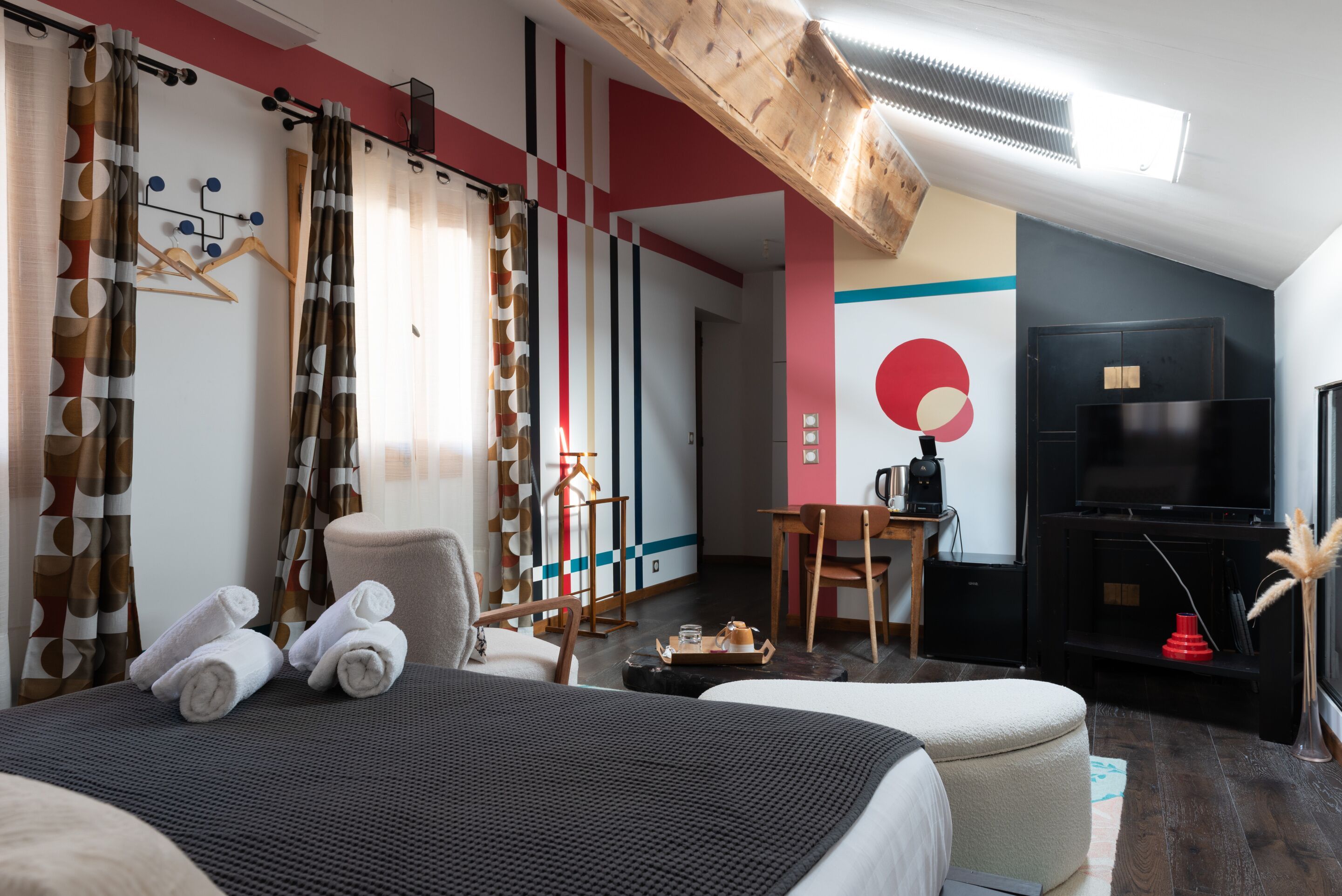 A hotel room with a bed, a desk, a chair, a TV, and a large window.