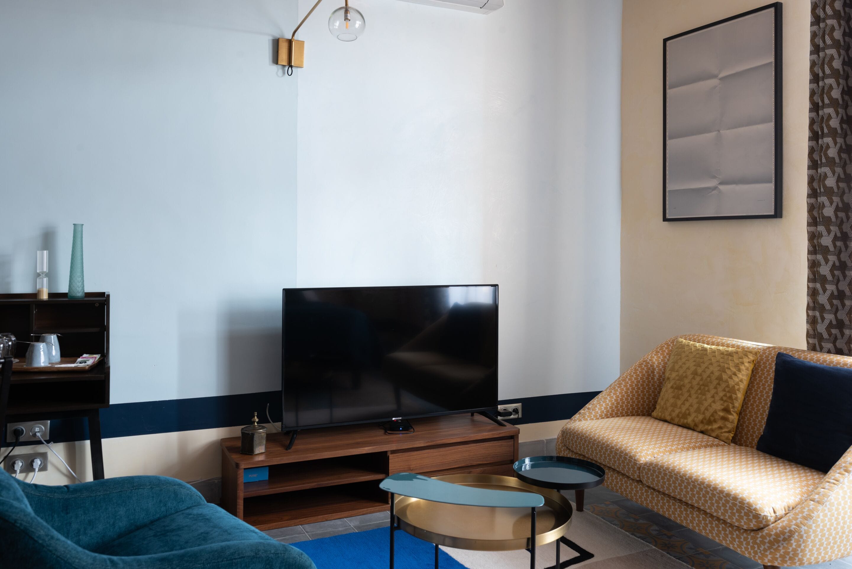 A living room with a flat-screen TV, a sofa, a coffee table, and a bookshelf.