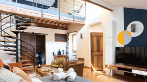 A spacious living area with a spiral staircase, a flat-screen TV, and a dining area. - La Maison des Seigneurs (Cucuron)