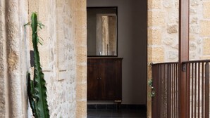A narrow stone corridor with a potted cactus, a wooden bench, and a metal railing. - La Maison des Seigneurs (Cucuron)