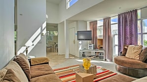 A modern living room with a brown sofa, a glass coffee table, and a flat-screen TV.