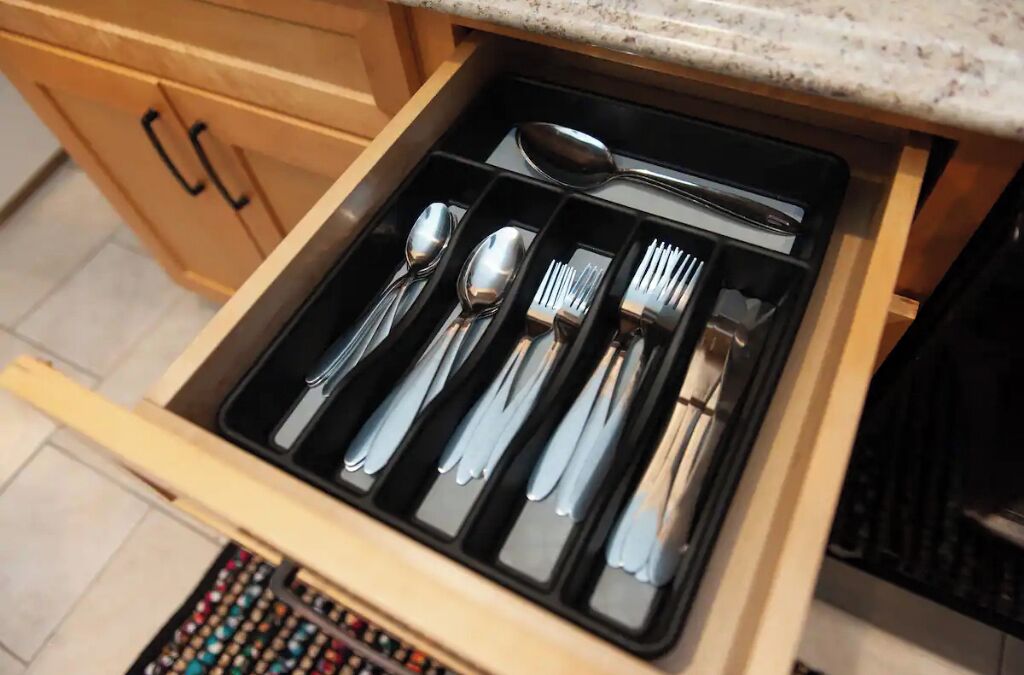A drawer with neatly organized cutlery including spoons, forks, and knives.