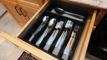 A drawer with neatly organized cutlery including spoons, forks, and knives.