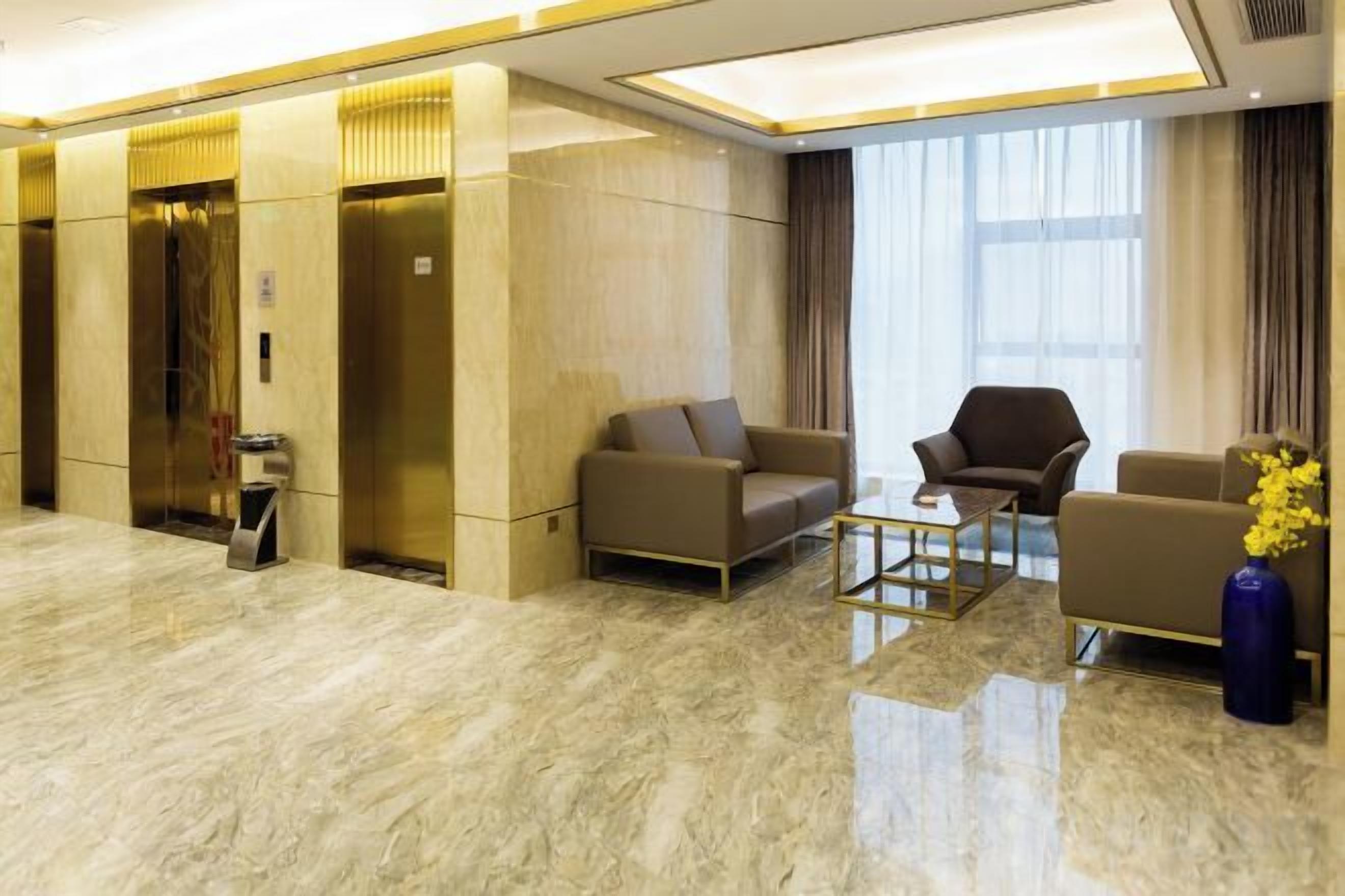 A modern lobby with a marble floor, two sofas, a coffee table, and a vase with flowers.