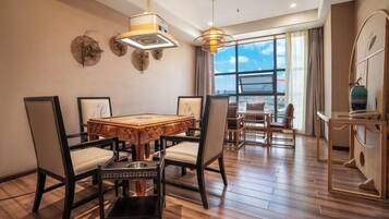 Un comedor con una mesa y sillas de madera, una lámpara de araña y vistas a través de ventanas amplias.