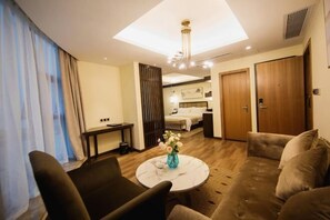 A hotel room with a sofa, a round coffee table with a vase, a bed, a desk, and a wardrobe. - Binjiang Celebrity Holiday Hotel (Nanbu County)