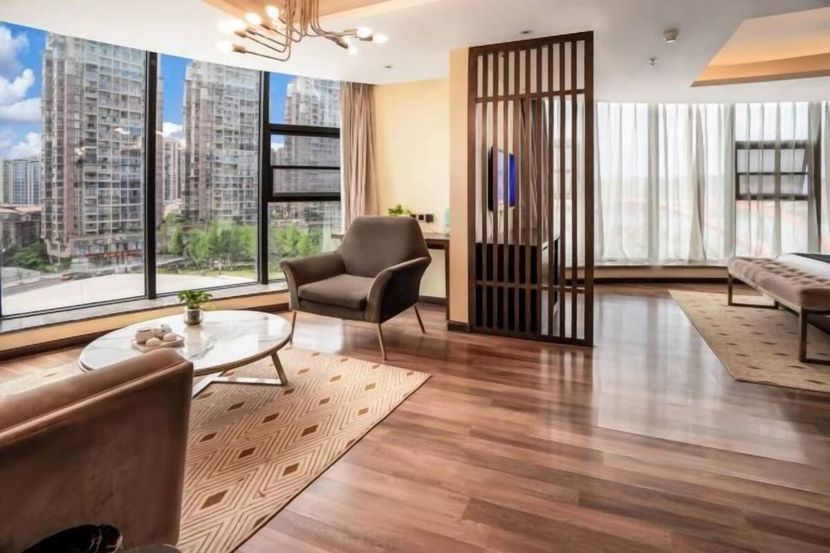Una sala de estar moderna con un ventanal grande, un sofá, un sillón, una mesita de centro y un separador decorativo.