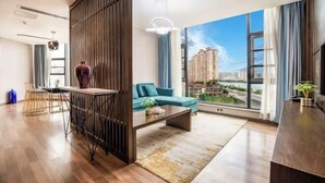 Una sala de estar moderna con un sofá, una mesita de centro y vistas a un paisaje urbano a través de amplias ventanas.
