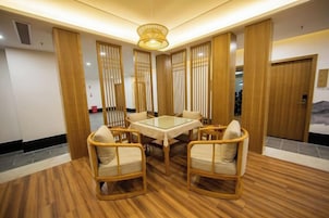 Un comedor con una mesa redonda y cuatro sillas, suelo de madera y una lámpara decorativa en el techo.