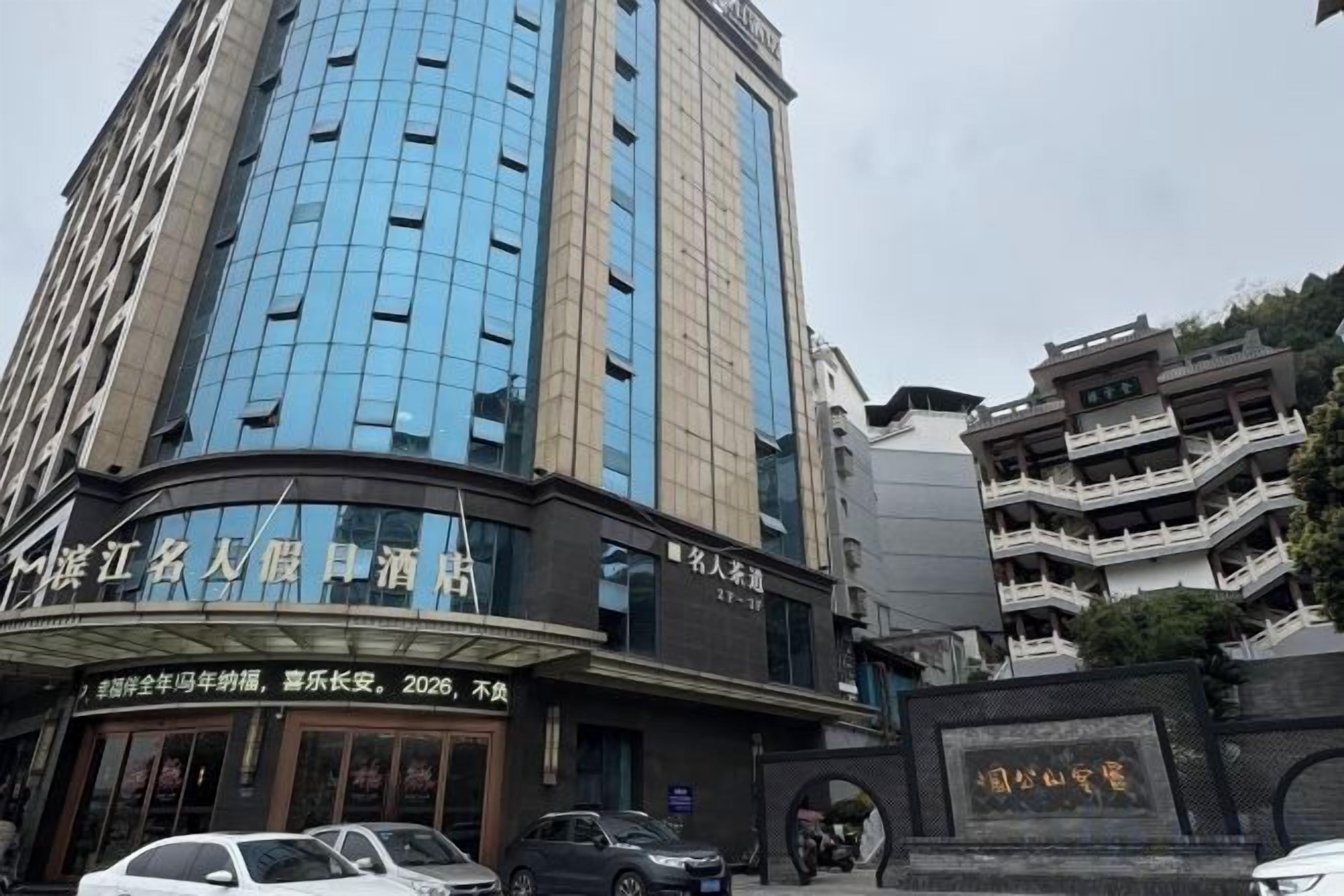Hotel con fachada moderna, entrada curva y cartel que indica una renovación en 2026.