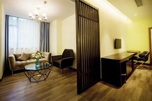 A modern living room with a sofa, armchair, and coffee table, a wooden desk, and a large window with curtains. - Binjiang Celebrity Holiday Hotel (Nanbu County)