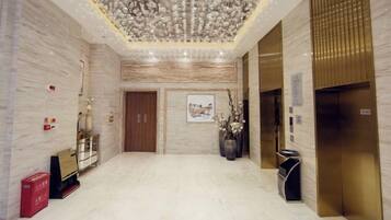 Eine Hotelhalle mit Marmorböden, einem Chandelier, Holztüren und einer Rezeption.