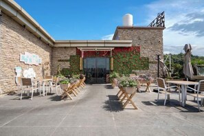 An outdoor patio area with tables and chairs, a brick building, and a clear sky. - Binjiang Celebrity Holiday Hotel (Nanbu County)