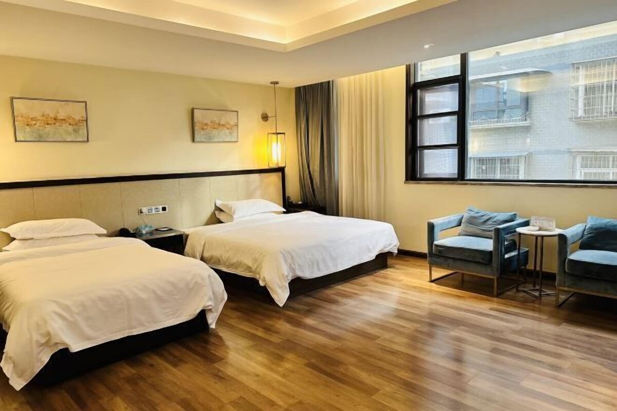 A hotel room with two beds, a small table, and a chair.