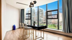 Una habitación moderna con un ventanal grande, una mesa de comedor, dos sillas y una botella de agua azul.
