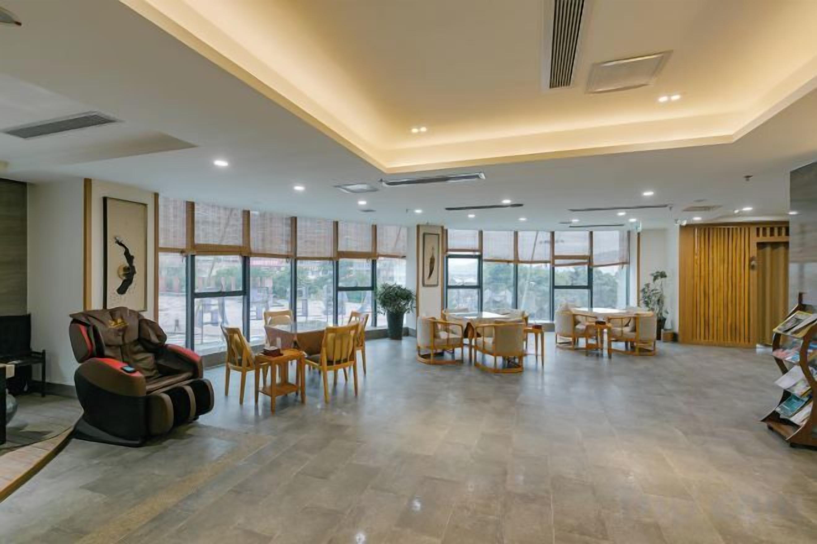 Un hall d’hôtel spacieux, doté d’un comptoir d’accueil, d’un espace salon et de grandes fenêtres.