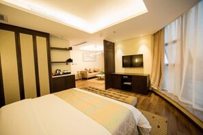Una habitación de hotel con cama, escritorio, televisor y sofá.