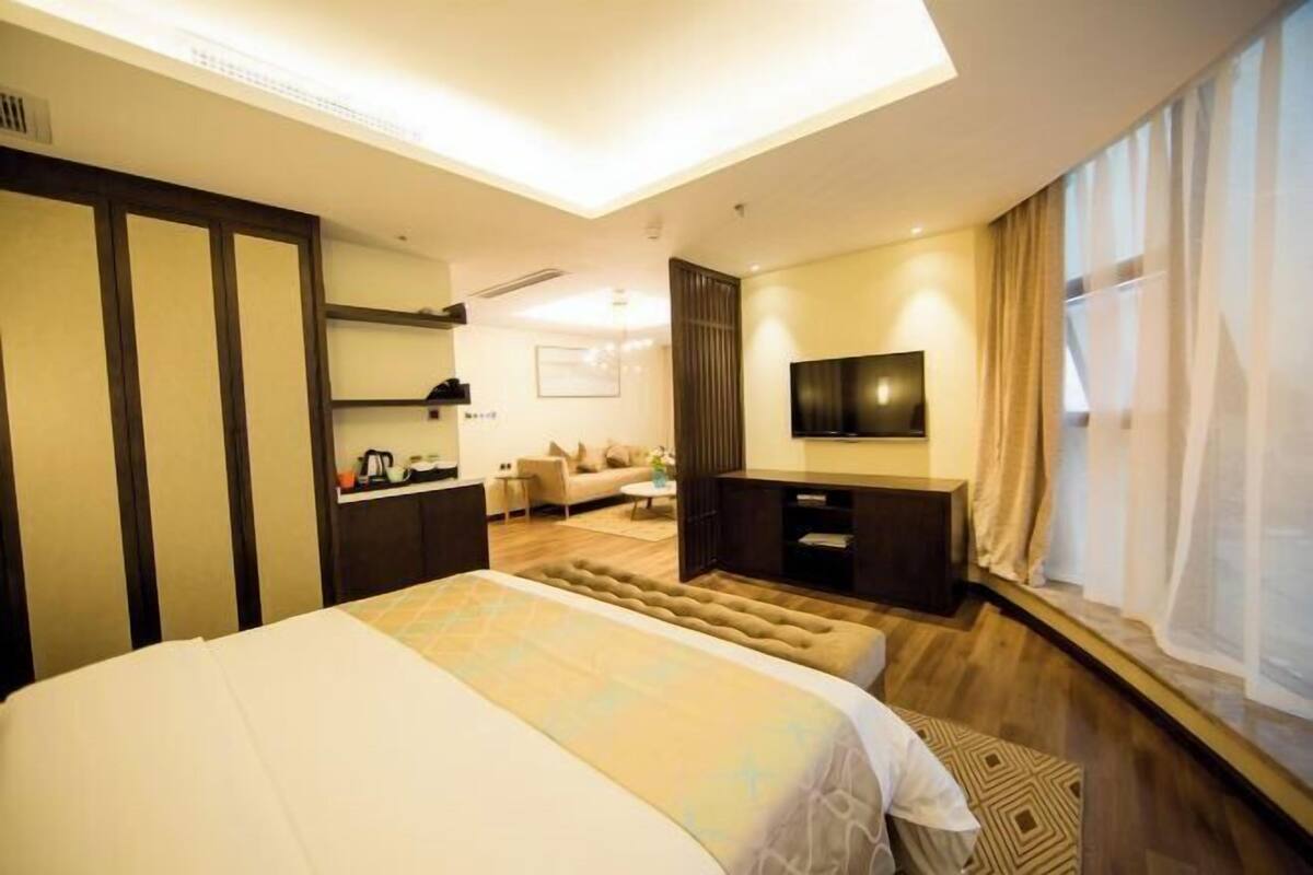 Una habitación de hotel con cama, escritorio, televisor y sofá.