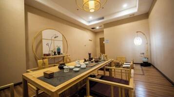 A dining area with a long table, chairs, and a large mirror.
