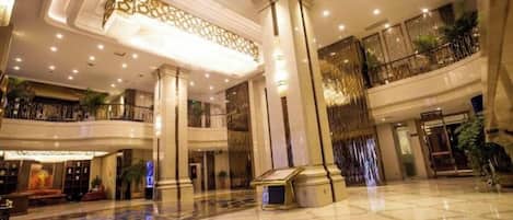 A spacious lobby with a high ceiling, large columns, and a polished floor.