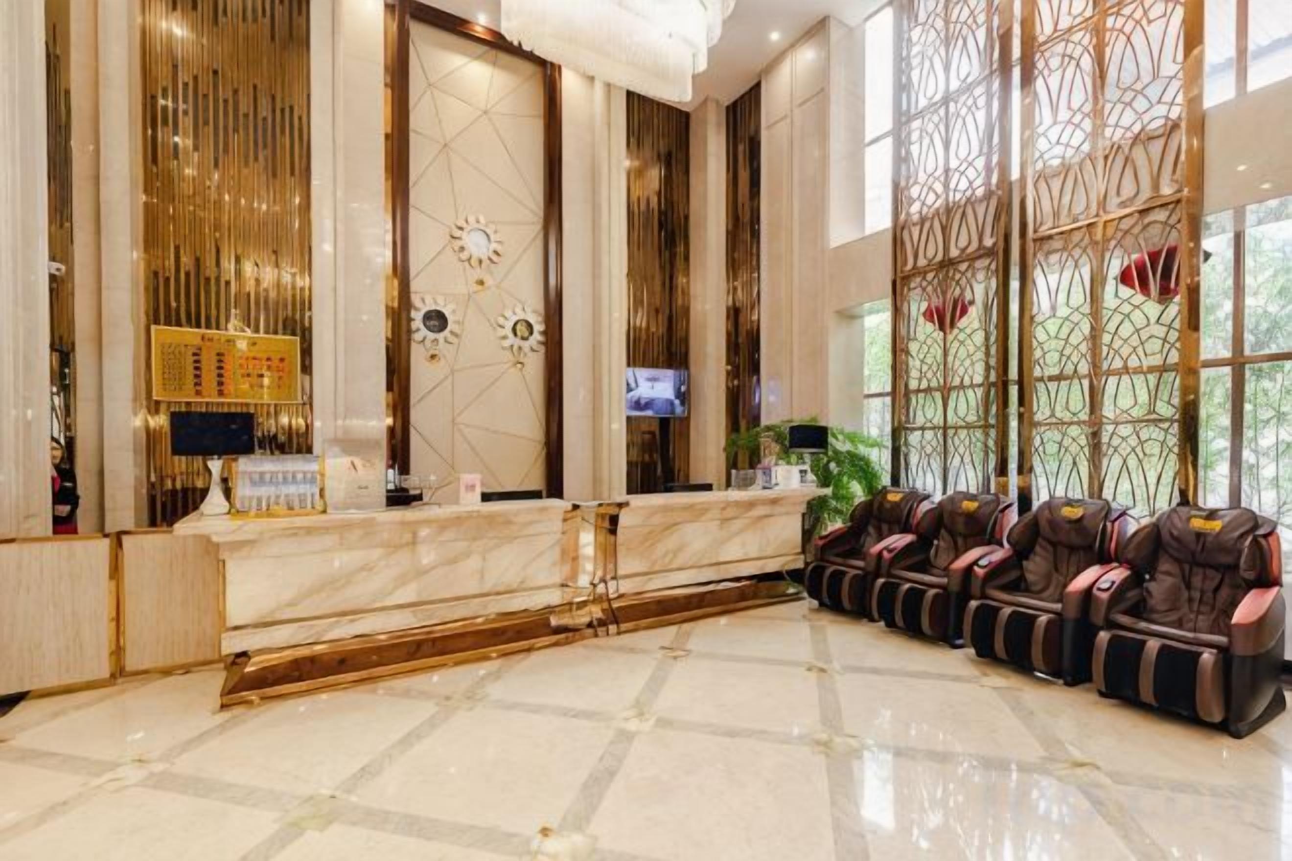 A hotel reception area with a marble counter, massage chairs, and a large window with decorative glass panels.