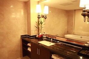 Une salle de bain avec un comptoir en marbre, un lavabo, un miroir et une baignoire.