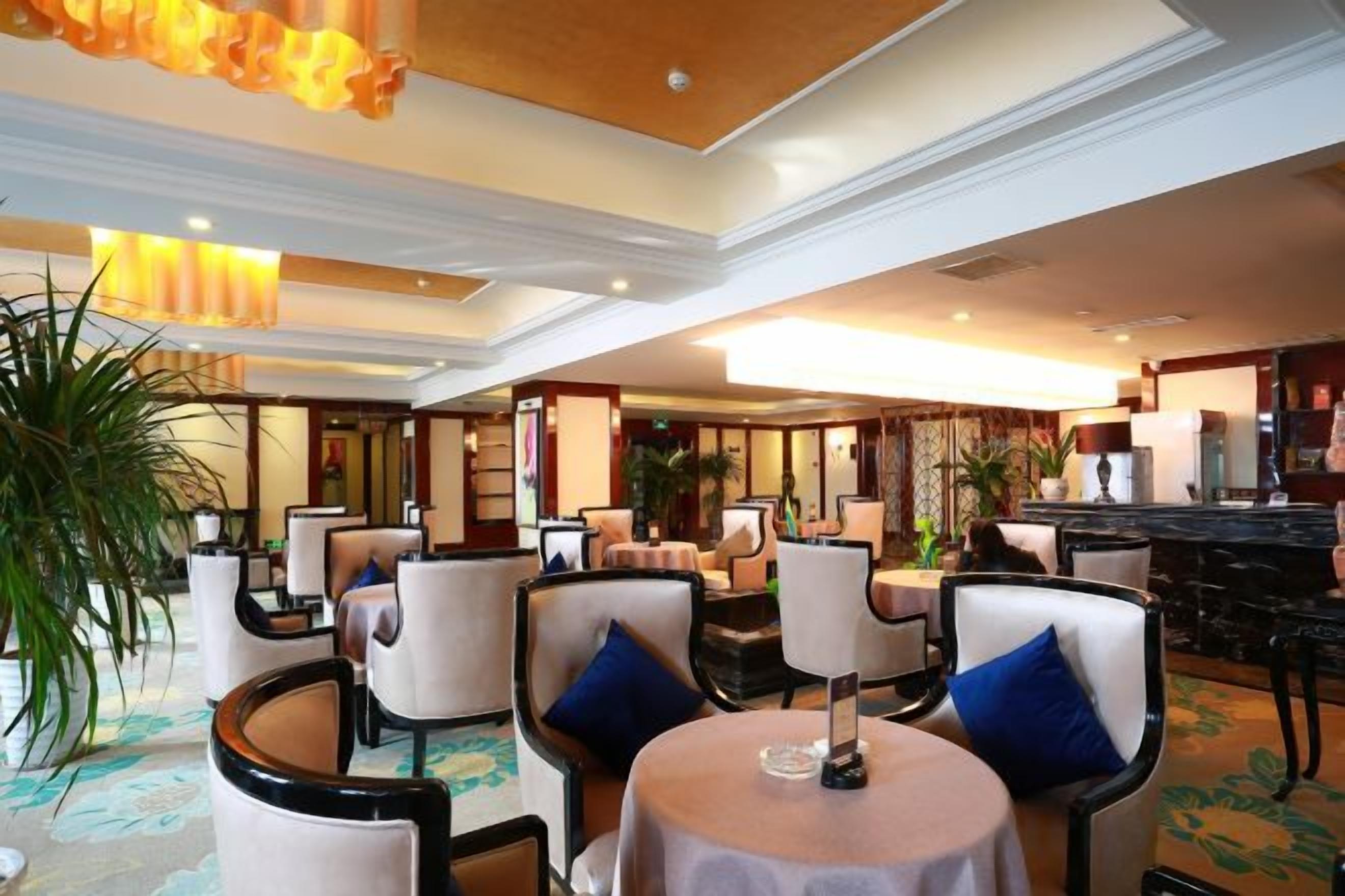 A hotel lobby with round tables, chairs, and a bar area.