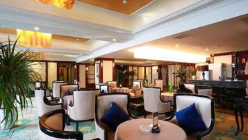 A hotel lobby with round tables, chairs, and a bar area.
