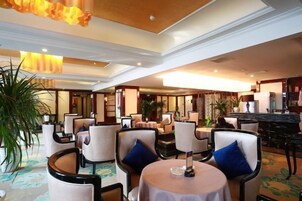Un vestíbulo de hotel con mesas redondas, sillas y una zona de bar.