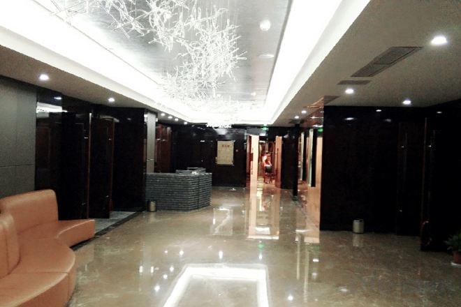 Rebedor d'hotel amb un sòl brillant, zona de seients i un llum decorativa al sostre.