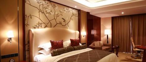 A hotel room with a large bed, a desk, a chair, and a wall with a floral design.