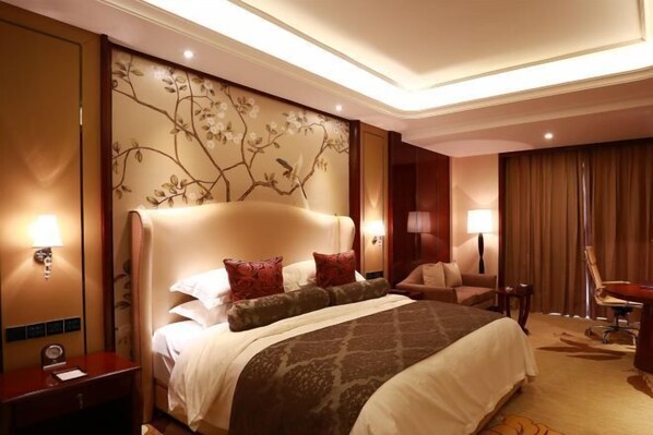 Habitación de hotel con una cama grande, un escritorio, una silla y un diseño floral en la pared.