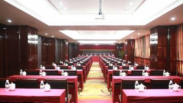 A conference room with rows of tables, each with a red tablecloth and water bottles.