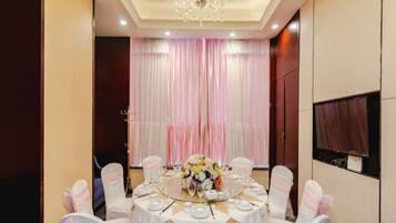 A banquet hall with round tables, white tablecloths, and pink chairs.