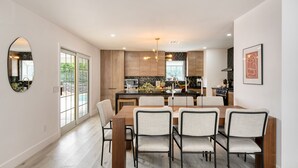 A modern kitchen with wooden cabinets, a central island, and a dining area with a wooden table and chairs.