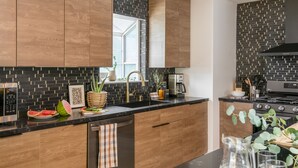 A modern kitchen with wooden cabinets, a black backsplash, and stainless steel appliances.