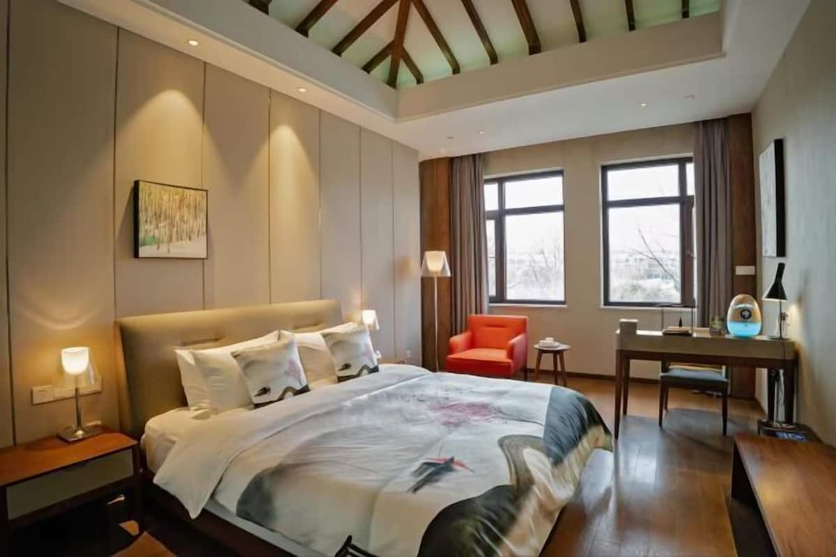 Ein Hotelzimmer mit Bett, Schreibtisch, Stuhl und großen Fenstern.