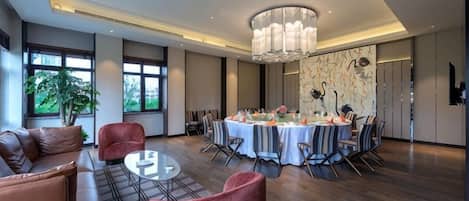 A modern dining area with a round table, chairs, and a chandelier.
