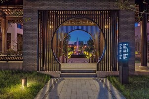 Entrada de um edifício com arco circular e caminho que a leva até ele.