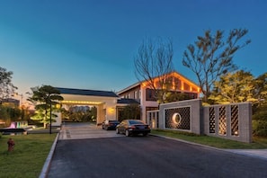 A modern hotel with a well-lit entrance, a gated driveway, and a parking area. - Sunshine Peninsula Jinsha Hotel (Zhangjiagang)